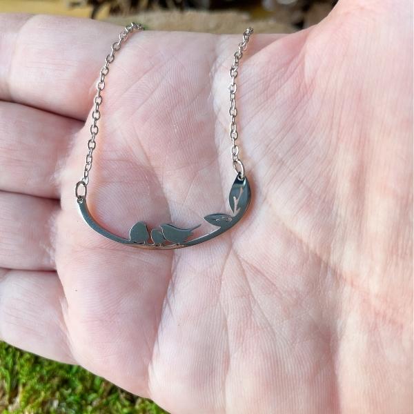 three little birds necklace in a hand