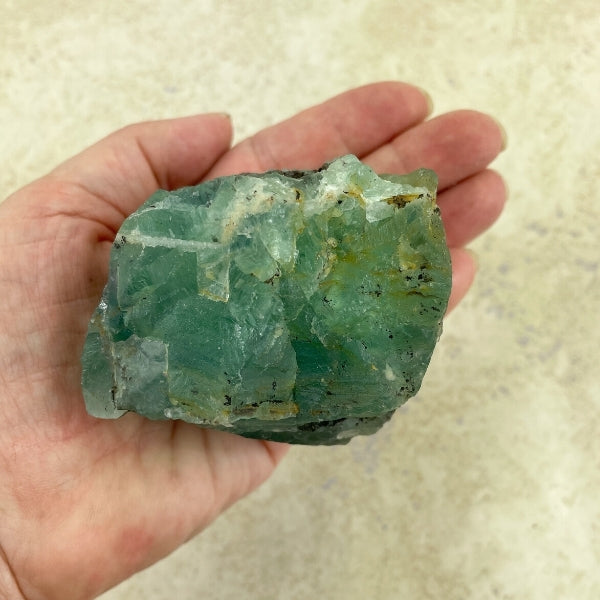 green fluorite stone in the palm of a hand