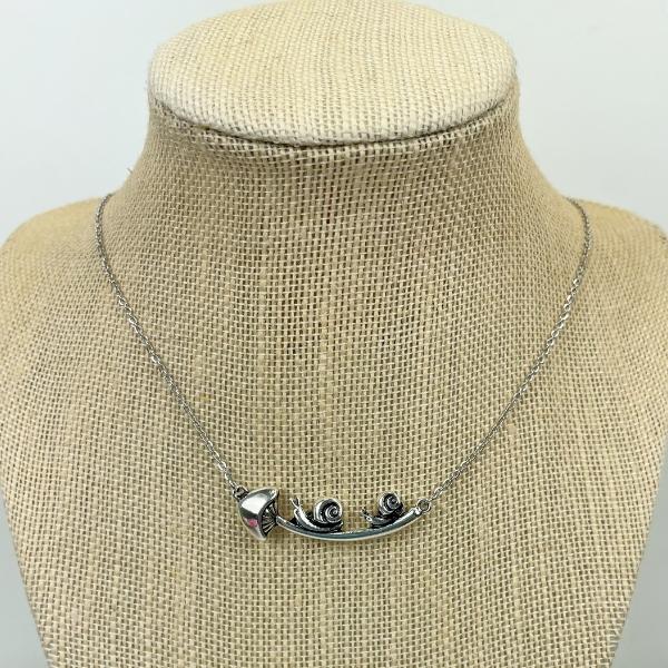 snail and mushroom necklace on a jewelry display